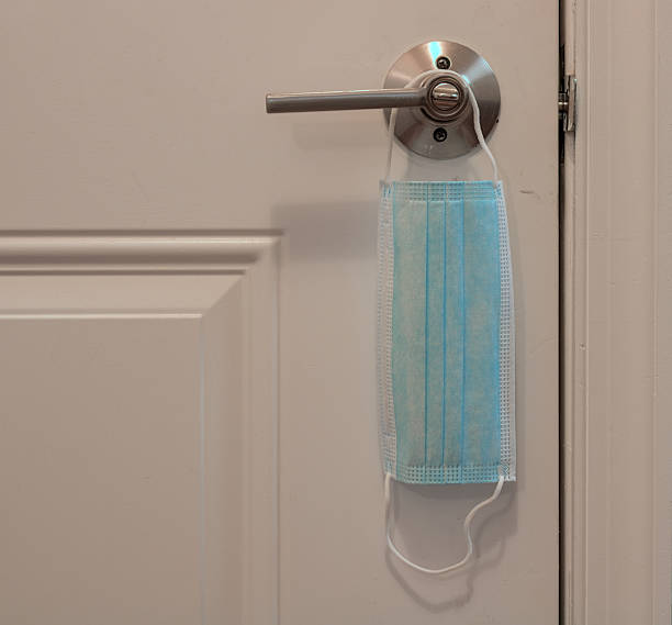 istock Single White Medical Face Mask Hanging On A Metal Door Handle. 2238519165