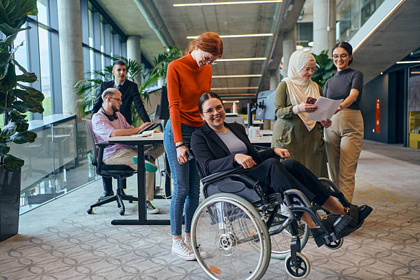 istock A diverse group of business colleagues is having fun with their wheelchair-using colleague, demonstrating their attention and inclusivity in the workplace 2238519829