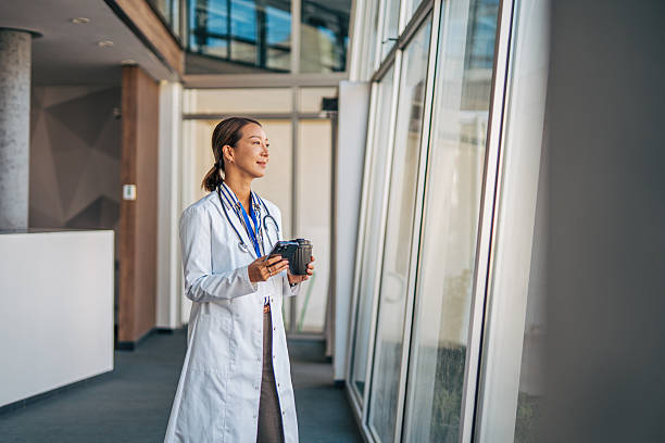 istock Female doctor looking out window during coffee break 2238524675