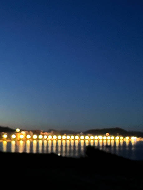 Nighttime view of a coastal area with blurred lights illuminating the seafront hotels. Abstract cityscape capturing the vibrant atmosphere of a seaside destination after dark.