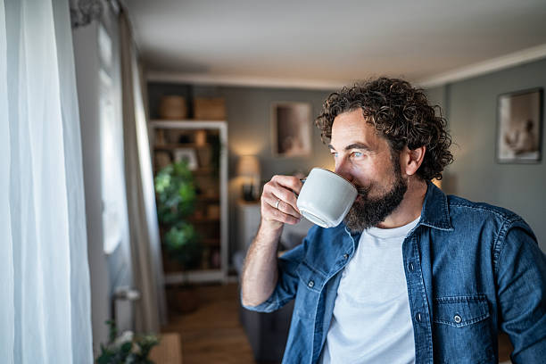 istock Man drinking coffee at home looking out window 2238528761