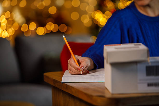 istock A person writes in a notebook with a pencil at a warm, festive desk setting 2238531516