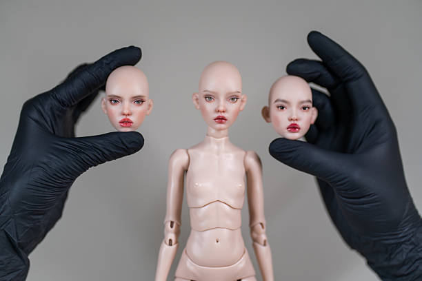 istock Ball jointed doll and interchangeable heads held by black gloved hands 2238531759