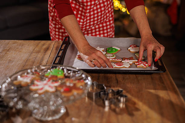 istock Holiday baking: hands arranging Christmas cookies on a parchment-lined tray in a red plaid apron 2238532094