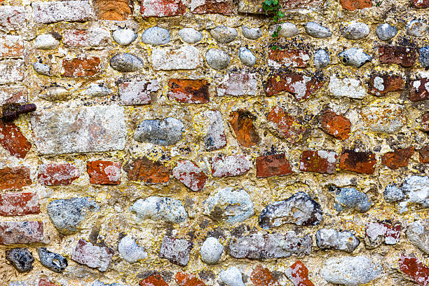 A full frontal, full frame image of a very old and weathered red brick and cobble stone wall.  Ideal for a background with lots of copy space.