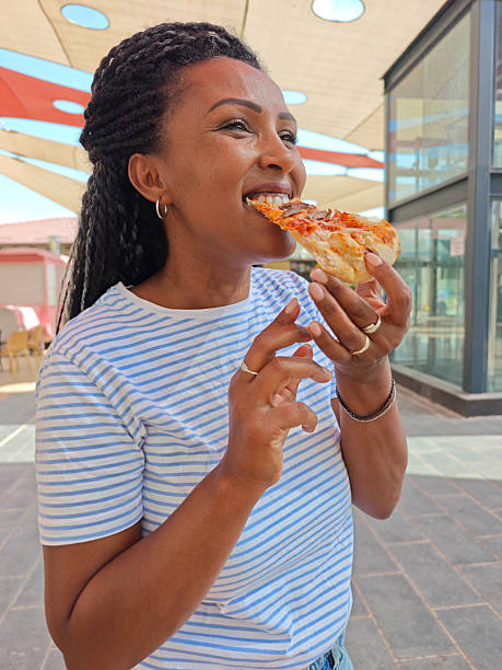 Smiling Woman Eating Pizza Outdoors.
