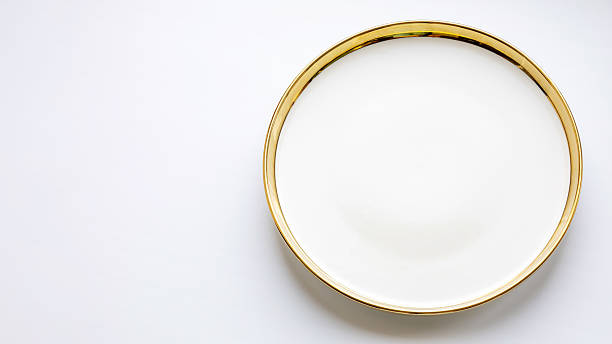 istock Simple white plate with gold rim placed on a light surface suitable for background 2238542718