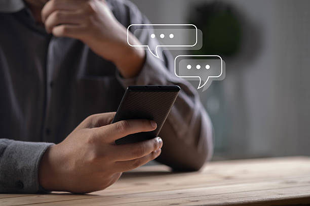 istock Person using smartphone with chat bubble icons, online messaging, mobile communication, social media chat, instant messaging, customer support, chatbot conversation, digital communication technology. 2238543120