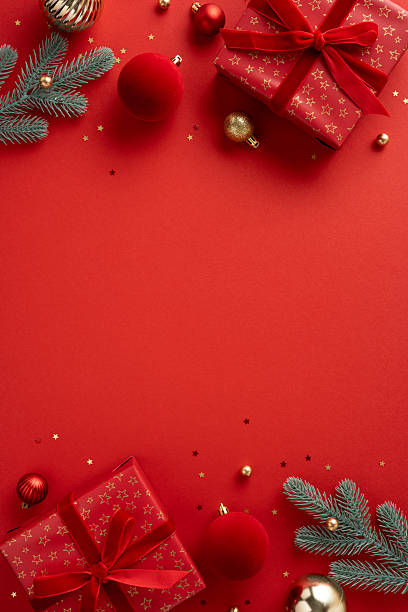 istock Red vertical themed Christmas scene featuring wrapped gifts, ornaments, pine branches and twinkling decorations evokes festive mood and warm holiday greeting 2238543643