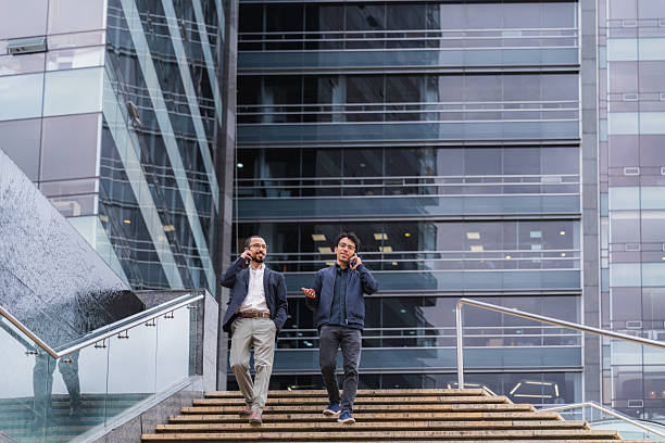 istock Young professionals walking, talking, and networking on cell phones 2238545071