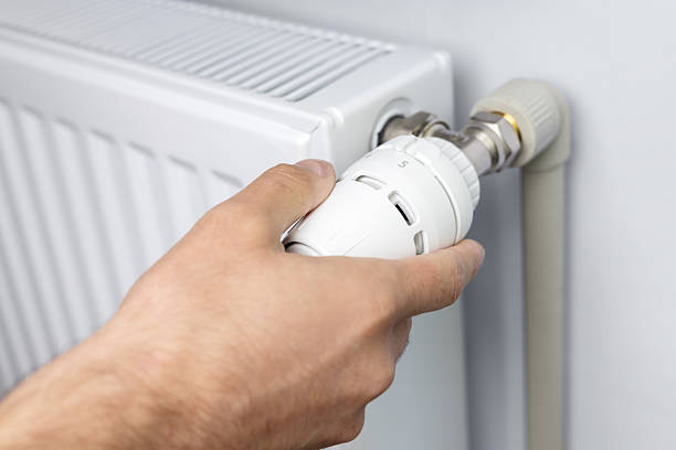 istock male's hand adjusting radiator temperature using thermostat. Home with central heating 2238545617