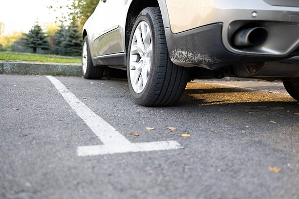 istock Car tire standing inside white marked parking spot on asphalt ground 2238548890