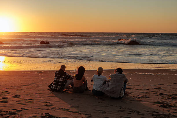 istock Friends watching golden sunset at beach: 2238550729