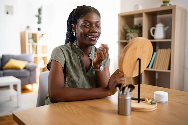 istock Young black woman applying makeup while sitting at a table at home 2238550940