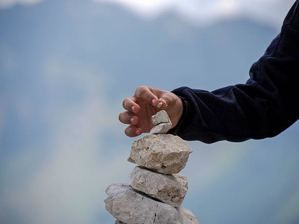 istock hand putting a very small tiny stone on stone pyramid in dolomites mountains 2238551068