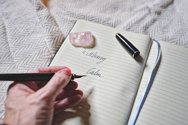 istock Hand writes in personal journal next to crystal on cozy blanket for self-care 2238554641