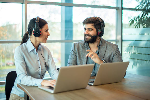 istock Female and male call center agents communicating with each other while working on laptops with headsets 2238555838