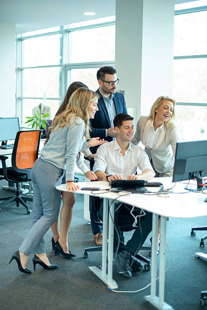 istock Group of business people gathered around young manager at computer discussing project in office 2238555839
