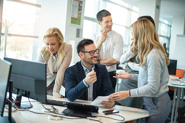 istock Business team gathered around leader at computer discussing project statistics and data in office 2238555924