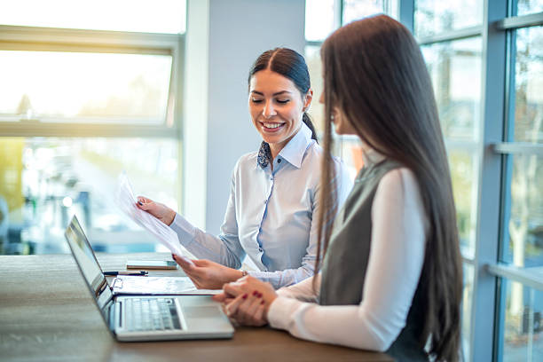 istock Female colleagues discussing business strategy while reviewing documents in bright modern office 2238556546