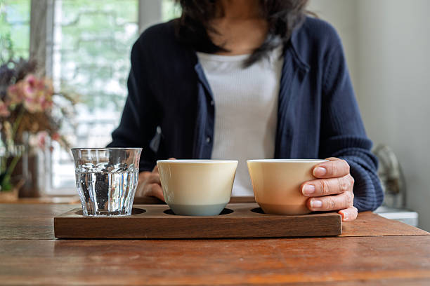 Mid adult Asian woman enjoying a coffee tasting experience with espresso, latte, and soda water in a cafe, representing modern coffee culture, lifestyle, and authentic everyday moments.