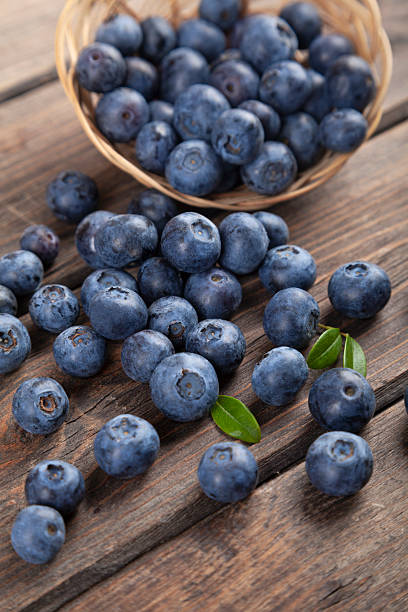 istock Blueberries with mint leaves scattered from basket on wooden rustic table 2238566554
