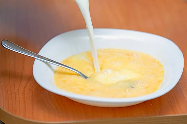 istock Pouring milk into beaten chicken eggs to prepare mixture for making an omelette 2238567288
