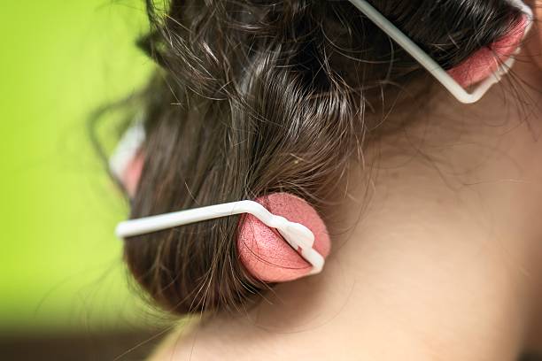 istock young girl with pink foam hair rollers and elastic bands for creating curls 2238567636