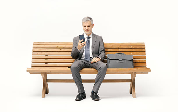 istock Businessman sitting on a bench and using a smartphone 2238569761