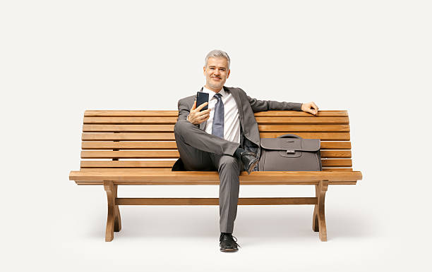 istock Businessman sitting on a bench and using a smartphone 2238570002