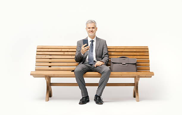 istock Businessman sitting on a bench and using a smartphone 2238570350