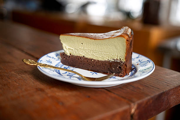 Close-up of a creamy pistachio burnt cheesecake slice served on a decorative plate with a golden spoon, showing indulgent dessert, sweet food, and modern cafe dining.