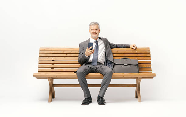 istock Businessman sitting on a bench and using a smartphone 2238570376