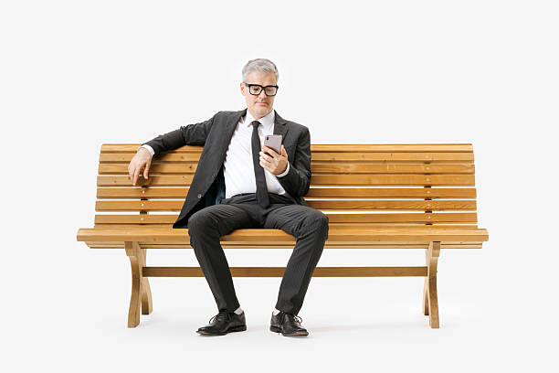 istock Businessman sitting on a bench and using a smartphone 2238570479