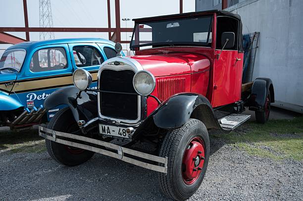 Osona, Spain – June 14, 2025: A front, low-angle view of a classic red and black Ford Model AA or BB truck with a chrome grille and bumper, parked at an outdoor car show.