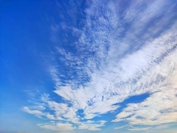 Bright blue sky with fluffy white clouds. Natural background with soft cloud shapes illuminated by sunlight. Perfect for weather, nature, and landscape themes.