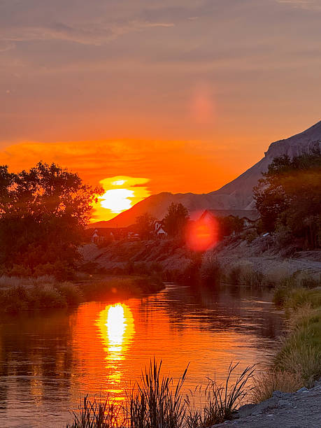 istock Fiery Sunset Over River with Silhouetted Trees and Mountain 2238577388