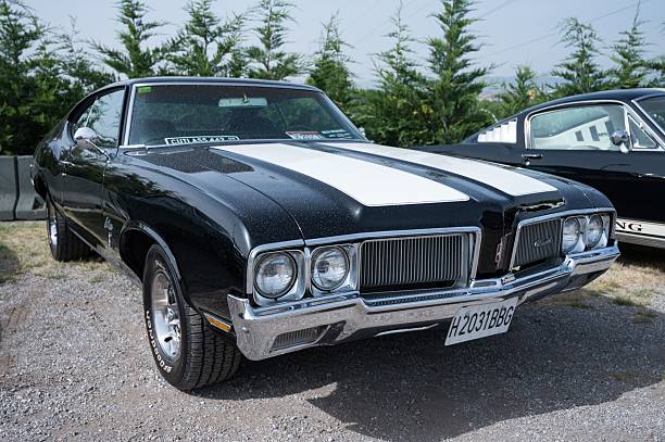 Vintage classic car in beautiful shiny black finish - shown from an angled rear view and cropped tightly.  In the vertical frame is shown most of the passenger side portion of the trunk and rear quarterpanel, including chrome side trim, the top of the rear fender and the rear side window.