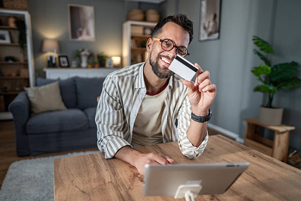 istock Smiling man holding credit card shopping online 2238582941