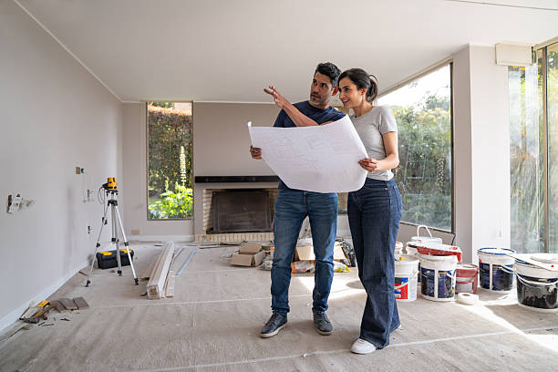 istock Couple remodeling their house and pointing at a wall while holding a blueprint 2238588107