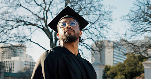 Man, college student and thinking outdoor for graduation at campus with memory, reflection or education. Person, happy and perspective for achievement at university, scholarship or learning