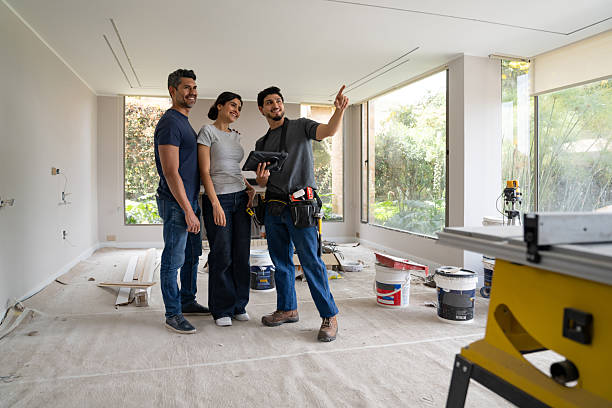 istock Construction worker pointing away while remodeling a house of a couple 2238592394