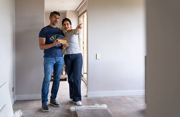 istock Couple pointing at a wall while choosing a color to paint their bedroom 2238592399