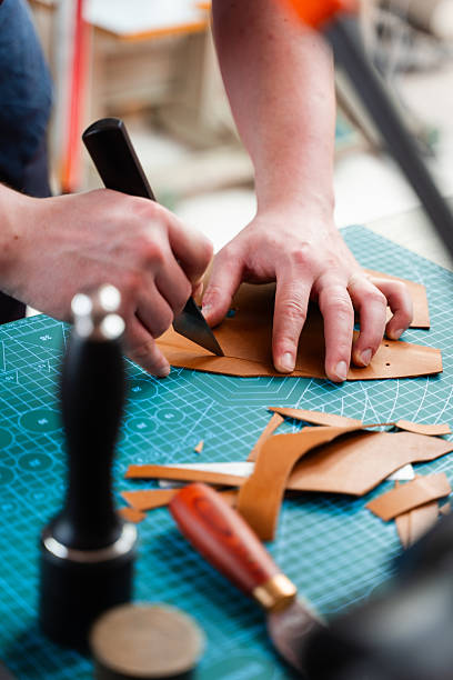 istock Cutting leather with knife. Craftsman carefully cuts leather with precision tools. Craftsman prepares leather pieces by cutting with precision, ensuring accurate templates for leather handmade goods. 2238599089