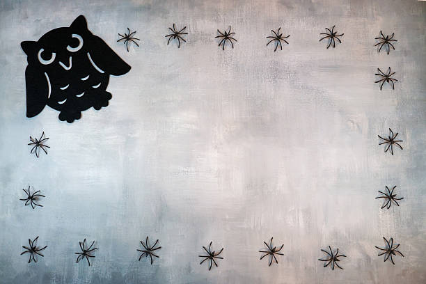 A black owl sits on a white background with a spider web. The owl is surrounded by a pattern of spider, which gives the image a terrible and terrible mood Halloween