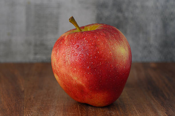 istock Red apple with water drops on wooden table 2238612083