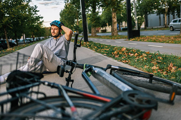istock Young man fallen from bicycle lying on sidewalk with helmet 2238616006