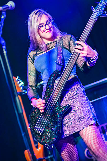 Young beautiful woman playing bass guitar in the studio.