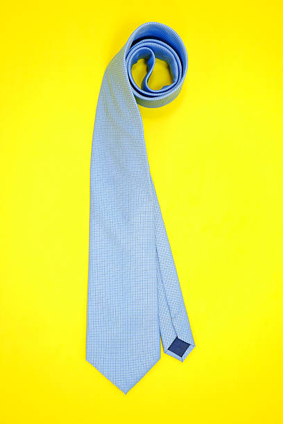 istock Necktie rolled on yellow background close-up view 2238622847