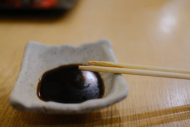 istock Chopsticks sit over a small square dish with dark soy sauce on a table 2238623569